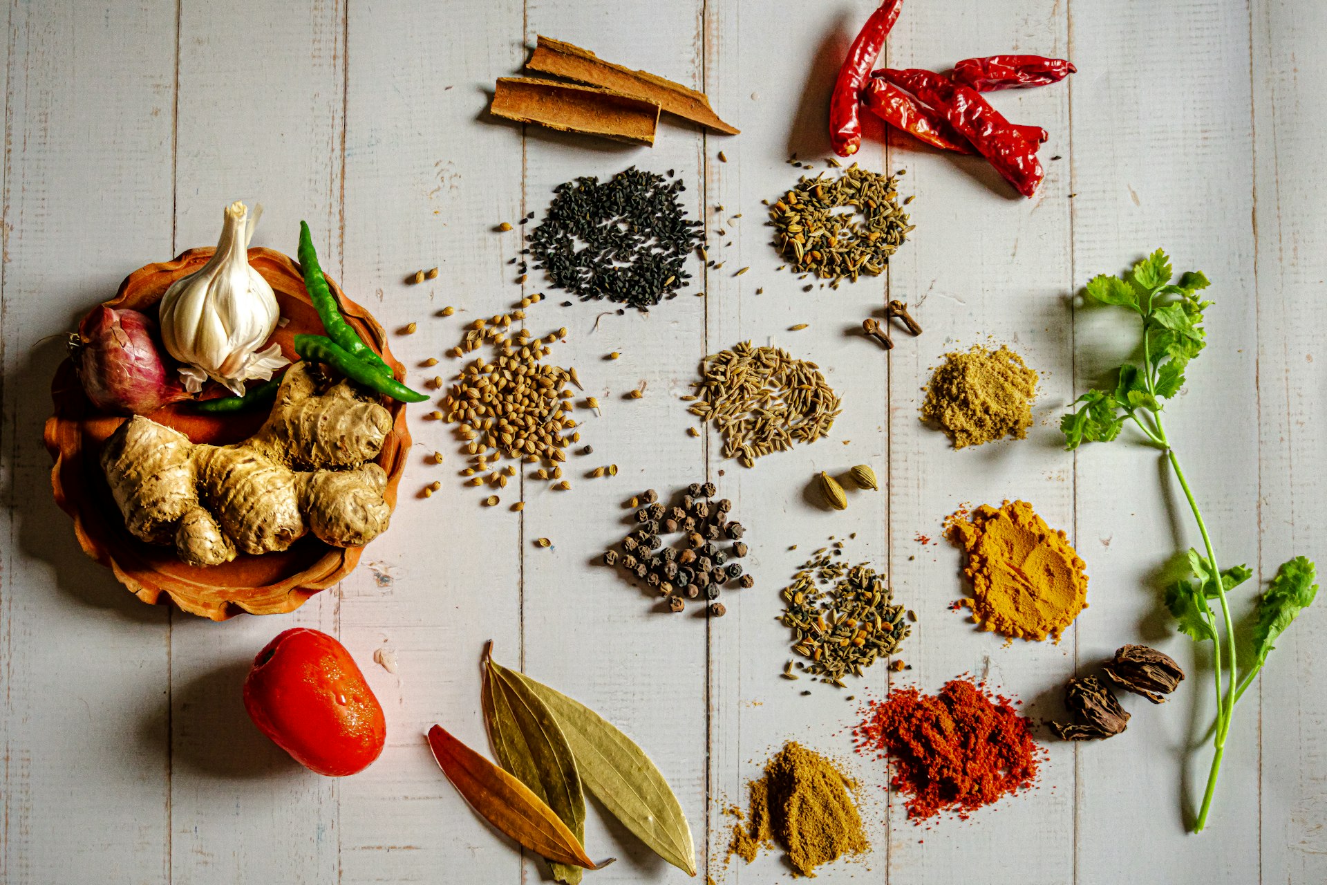 Whole spices and chillies laid out on wood